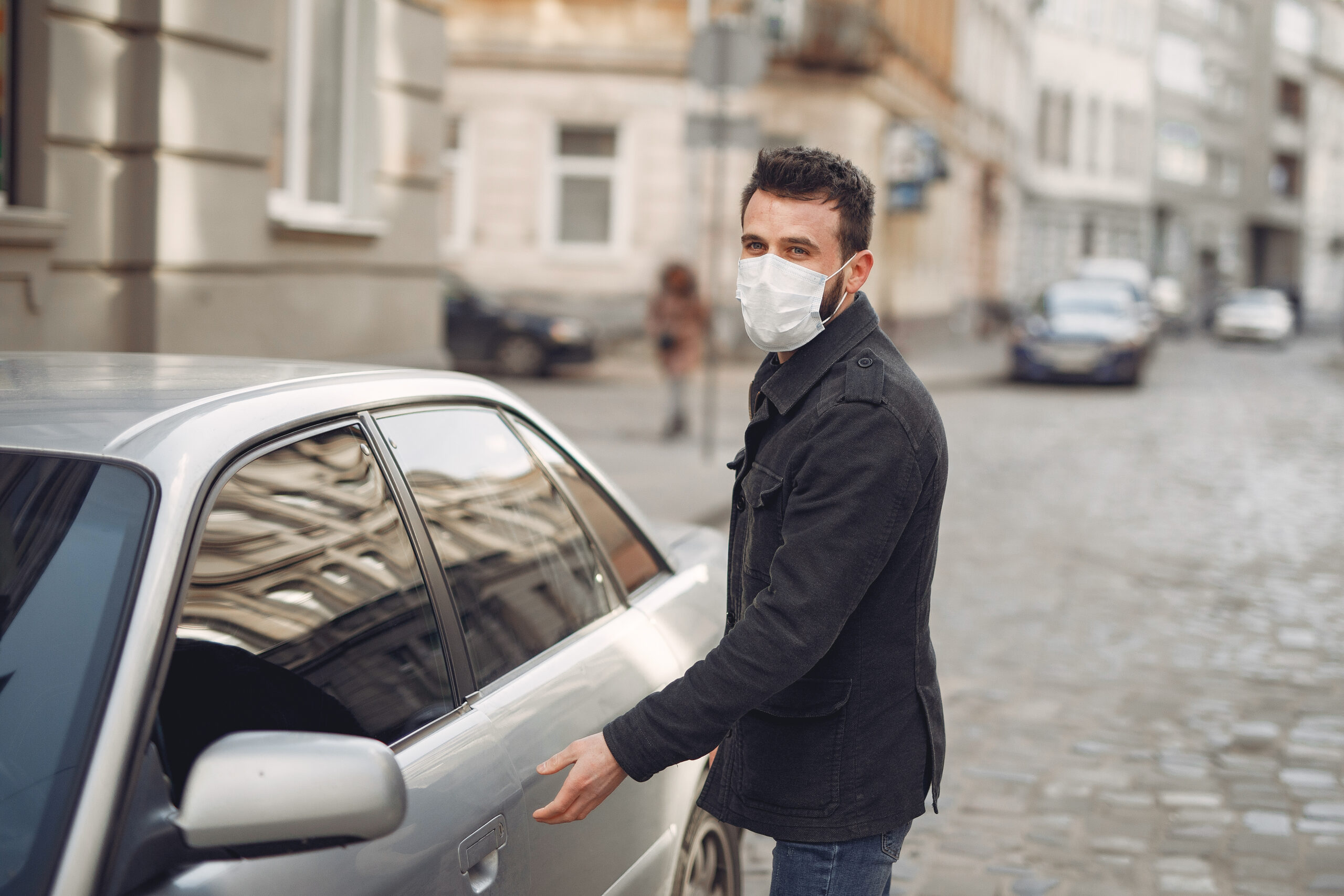 Man in a city. Person in a mask. Coronavirus theme. Man by the car.